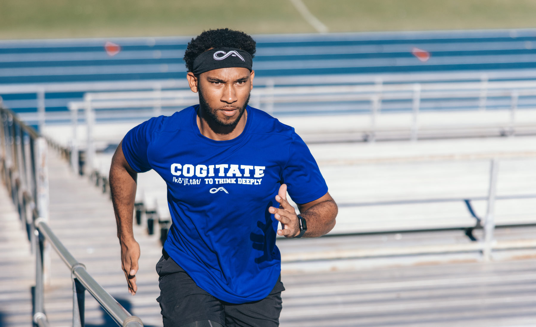 Athlete in a COGI shirt running up stadium bleachers